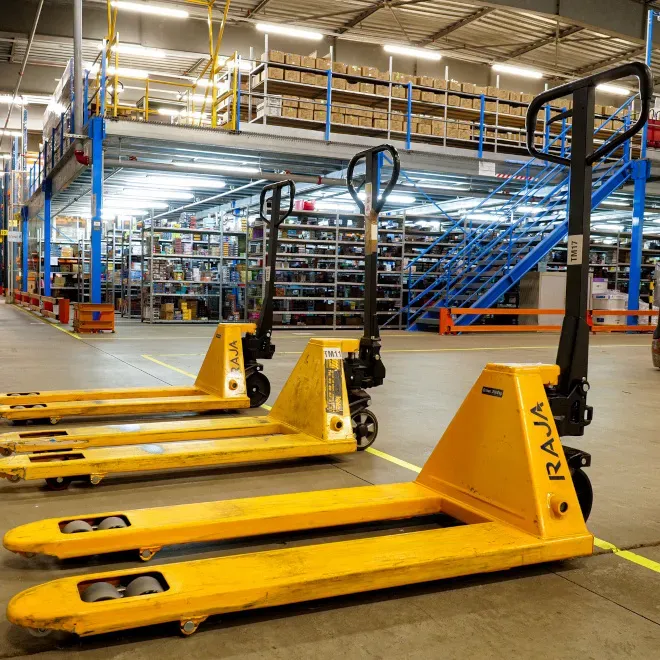 Transpalettes jaunes dans entrepôt logistique/Yellow pallet jacks in logistics warehouse